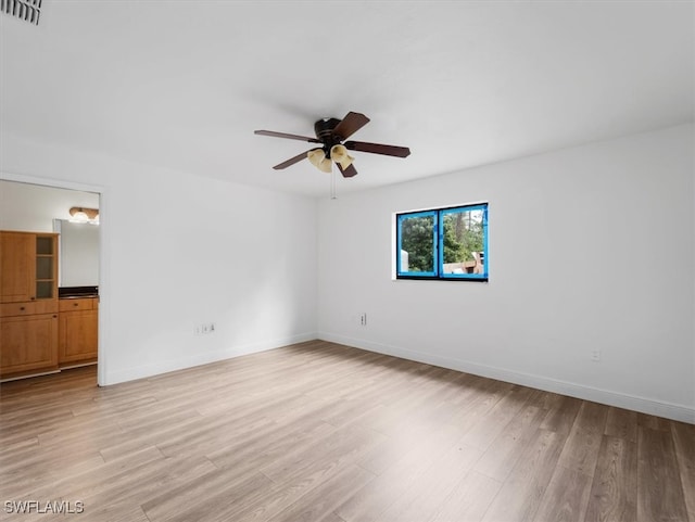 empty room with ceiling fan and light hardwood / wood-style flooring