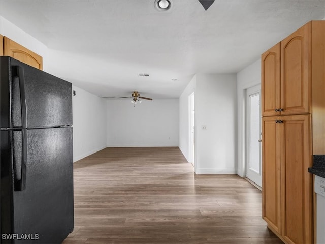 kitchen with ceiling fan, black refrigerator, and hardwood / wood-style floors