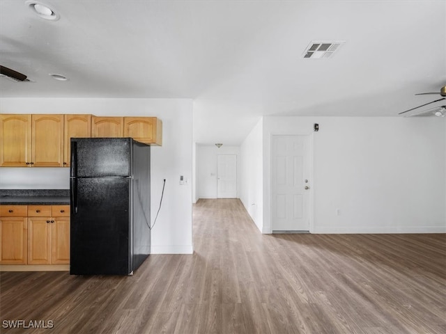 kitchen with light brown cabinets, dark hardwood / wood-style flooring, black fridge, and ceiling fan