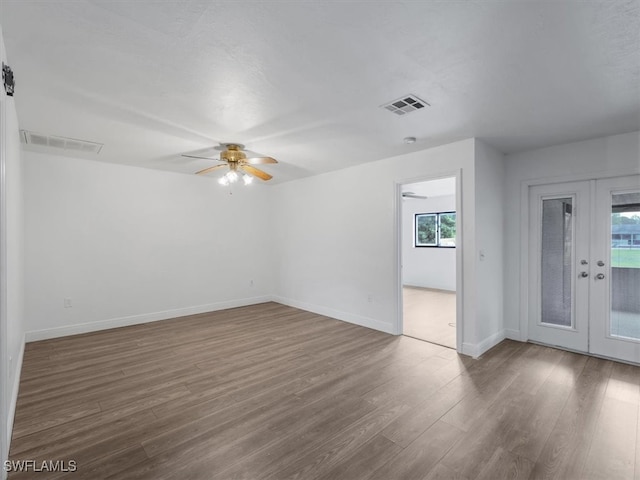 empty room featuring ceiling fan, dark wood-type flooring, and french doors