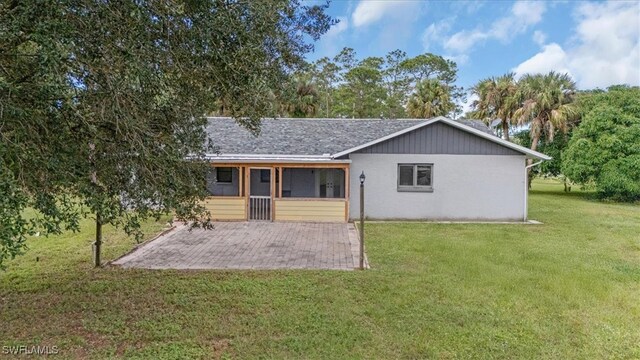 back of house with a lawn, a sunroom, and a patio