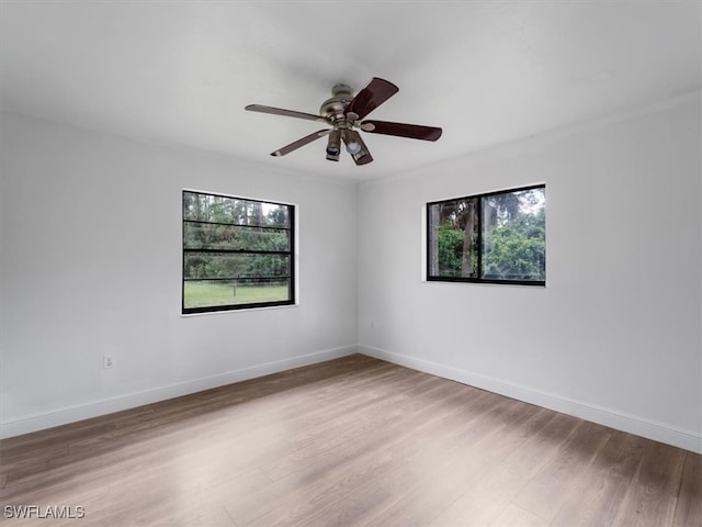 empty room with ceiling fan, a healthy amount of sunlight, and light wood-type flooring