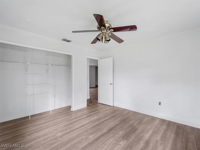 unfurnished bedroom featuring hardwood / wood-style flooring, ceiling fan, and a closet