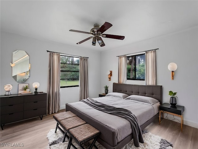 bedroom featuring ceiling fan, light hardwood / wood-style floors, and multiple windows