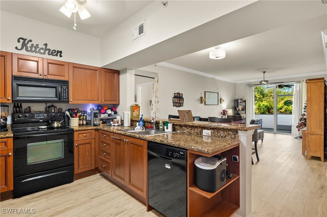 kitchen with sink, light hardwood / wood-style flooring, black appliances, kitchen peninsula, and dark stone counters