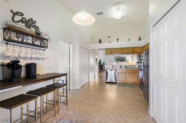 kitchen with sink, a kitchen bar, light tile patterned floors, a high ceiling, and stainless steel dishwasher