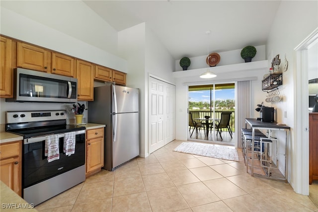 kitchen with stainless steel appliances, lofted ceiling, and light tile patterned flooring