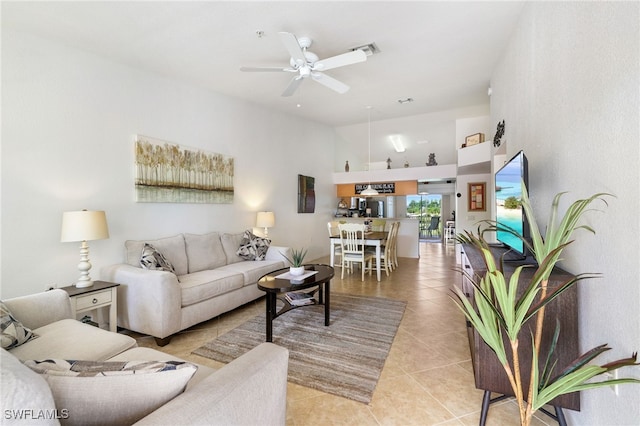 tiled living room featuring ceiling fan and a towering ceiling