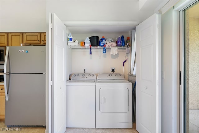 clothes washing area with light tile patterned flooring and independent washer and dryer