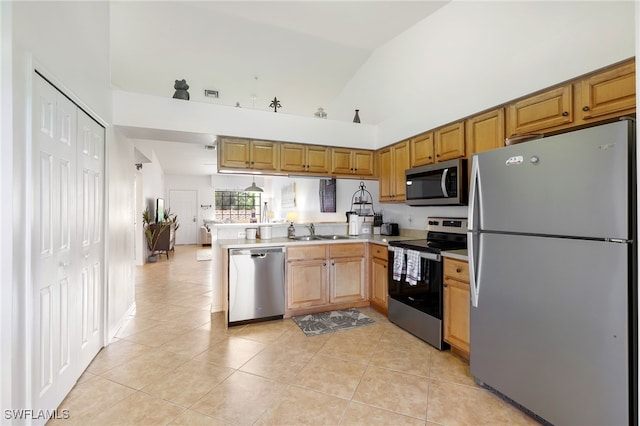 kitchen with light tile patterned floors, appliances with stainless steel finishes, kitchen peninsula, and lofted ceiling