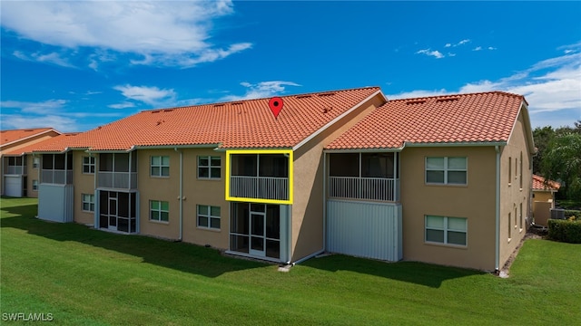 rear view of house featuring a yard and a balcony