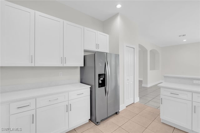 kitchen featuring stainless steel refrigerator with ice dispenser, light tile patterned flooring, and white cabinets