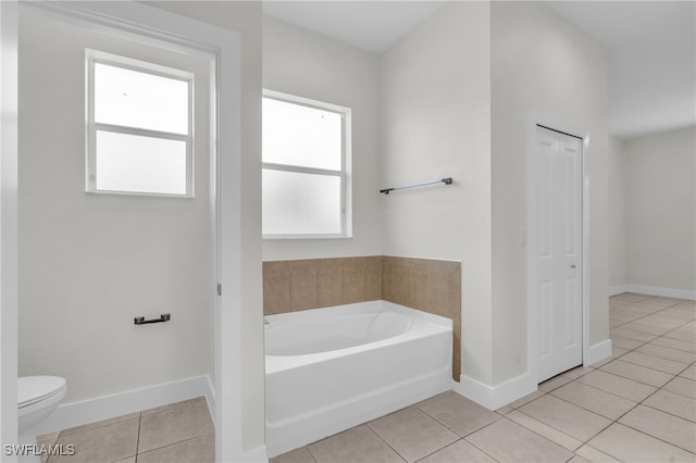 bathroom featuring tile patterned flooring, toilet, and a bath