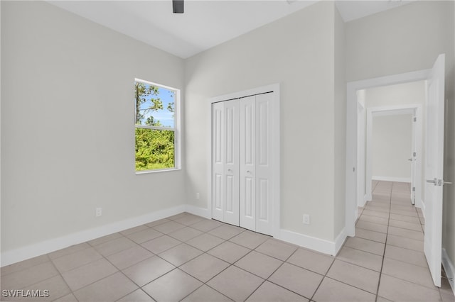 unfurnished bedroom with light tile patterned flooring, ceiling fan, and a closet