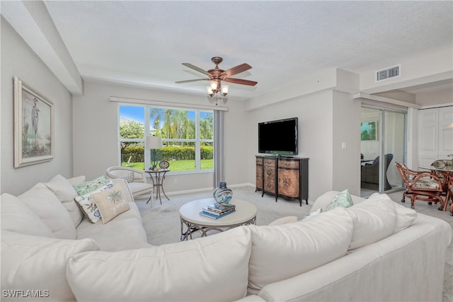 living room with light carpet, a textured ceiling, and ceiling fan