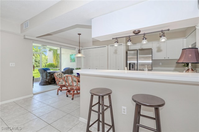 kitchen featuring a kitchen bar, light tile patterned floors, pendant lighting, white cabinets, and stainless steel fridge with ice dispenser