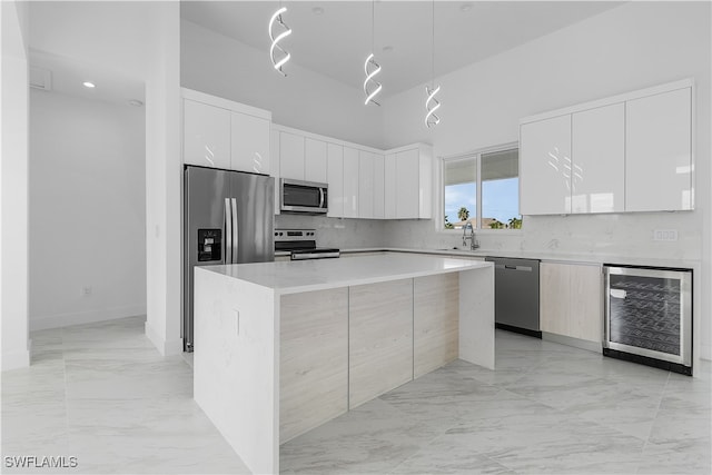 kitchen with wine cooler, stainless steel appliances, white cabinetry, and a kitchen island