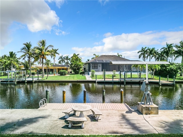 dock area with a lanai, a water view, and a lawn