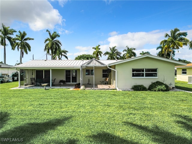 back of property with a lawn and a patio