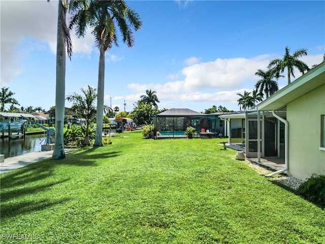 view of yard with a dock, a water view, a pool, and a lanai