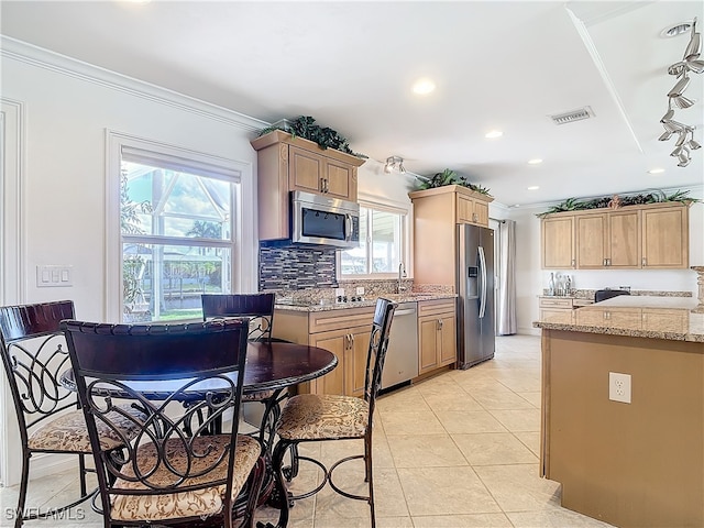 kitchen featuring ornamental molding, appliances with stainless steel finishes, and plenty of natural light