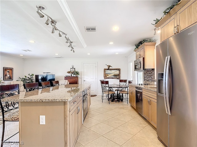 kitchen with appliances with stainless steel finishes, ornamental molding, a kitchen island, and a breakfast bar