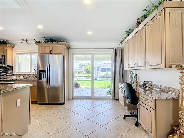 kitchen featuring built in desk, a healthy amount of sunlight, stainless steel appliances, and light stone counters