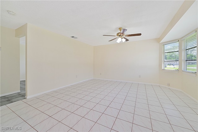 tiled empty room featuring ceiling fan and a textured ceiling