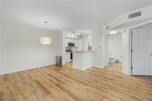 unfurnished living room featuring light hardwood / wood-style flooring and a textured ceiling