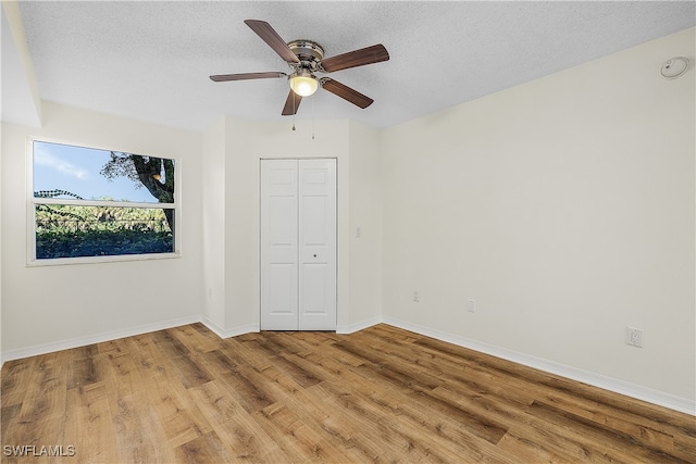 unfurnished bedroom with ceiling fan, a textured ceiling, light hardwood / wood-style floors, and a closet