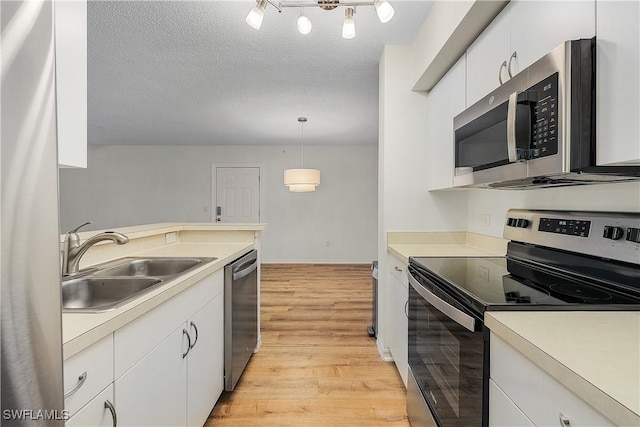 kitchen featuring sink, white cabinetry, hanging light fixtures, light hardwood / wood-style flooring, and stainless steel appliances