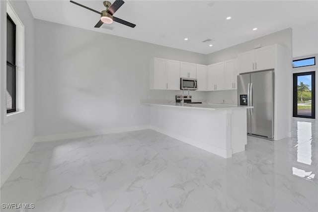 kitchen featuring stainless steel appliances, white cabinets, ceiling fan, and kitchen peninsula