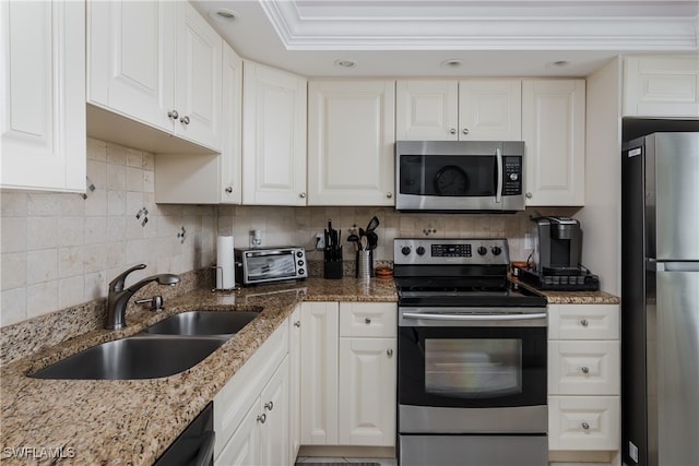 kitchen featuring decorative backsplash, white cabinets, light stone countertops, stainless steel appliances, and sink