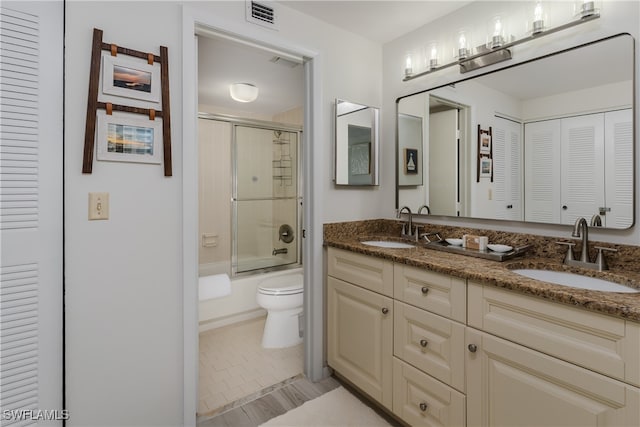 full bathroom featuring shower / bath combination with glass door, tile patterned flooring, vanity, and toilet