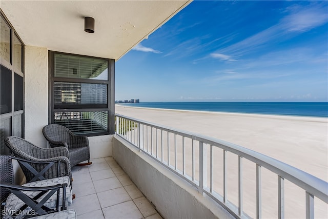 balcony with a water view and a view of the beach