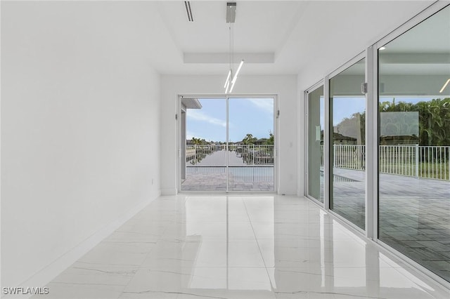 unfurnished room featuring baseboards, a tray ceiling, and a water view