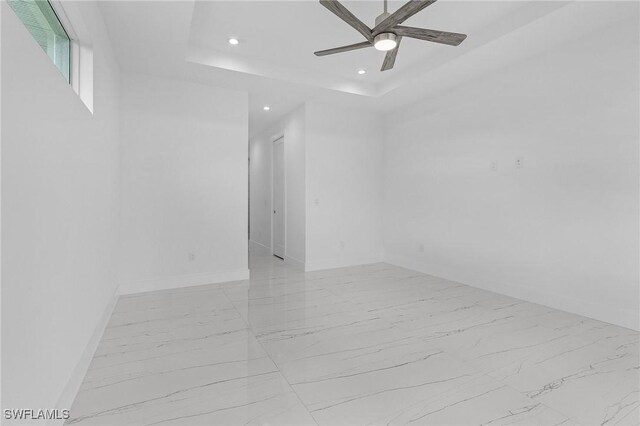 spare room featuring a tray ceiling and ceiling fan