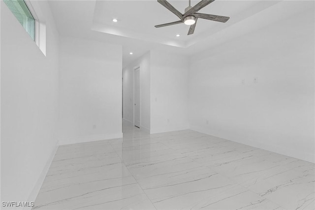 spare room with baseboards, recessed lighting, ceiling fan, a raised ceiling, and marble finish floor