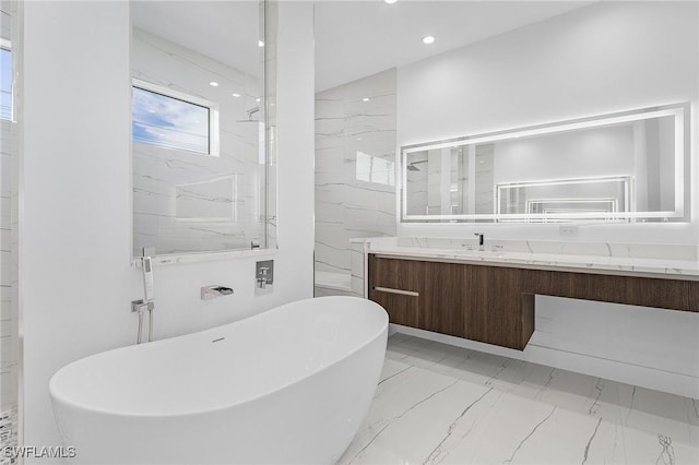 full bath with a marble finish shower, a freestanding bath, recessed lighting, marble finish floor, and vanity