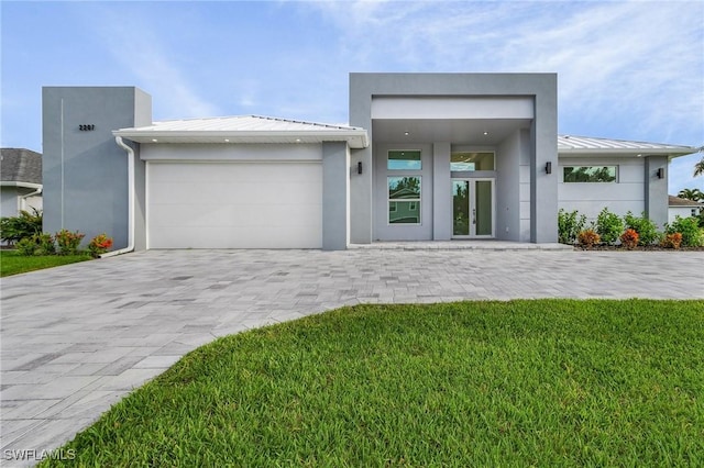 view of front of home with stucco siding, a standing seam roof, decorative driveway, french doors, and metal roof