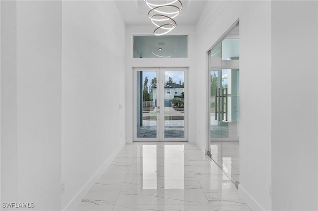 hall featuring baseboards, marble finish floor, and a chandelier