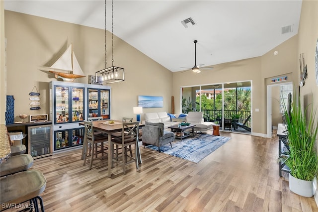 dining area featuring ceiling fan, high vaulted ceiling, beverage cooler, and light hardwood / wood-style floors