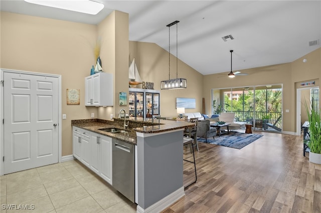 kitchen with a peninsula, white cabinetry, open floor plan, and a sink