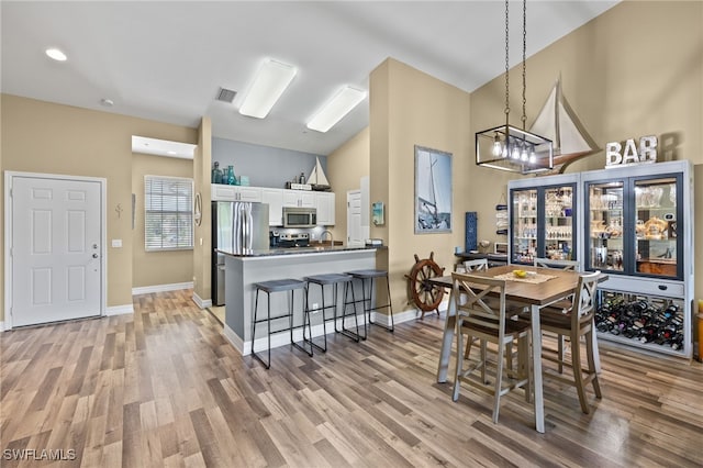 dining space with a chandelier, light hardwood / wood-style flooring, lofted ceiling, and sink