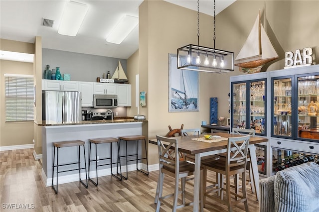 dining space featuring light wood-type flooring, visible vents, and baseboards