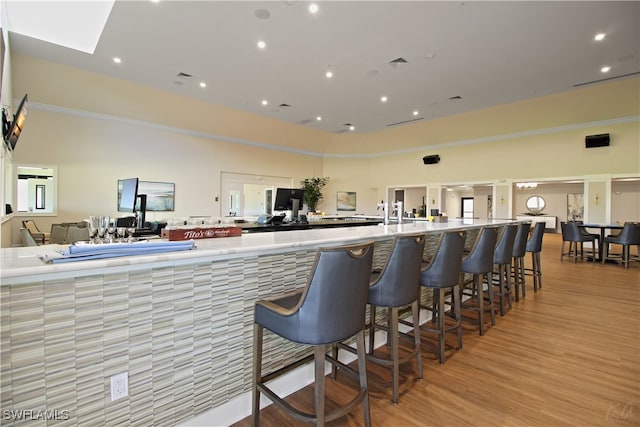 kitchen with a kitchen breakfast bar, light hardwood / wood-style floors, and a towering ceiling