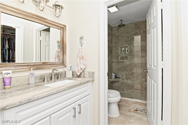 bathroom with a tile shower, tile patterned flooring, vanity, and toilet