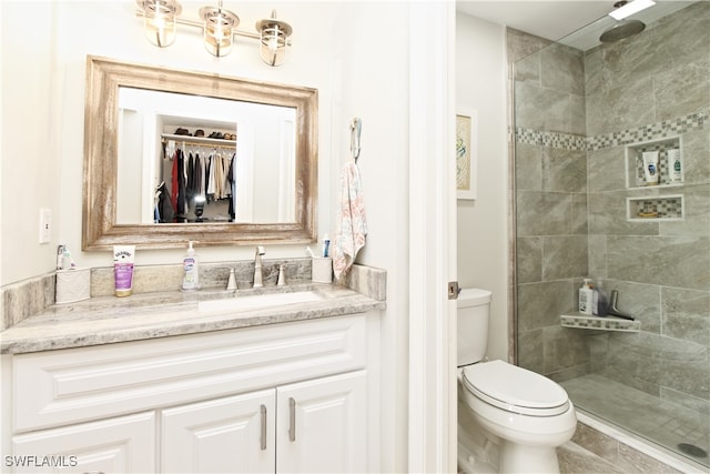 bathroom with walk in shower, vanity, and toilet