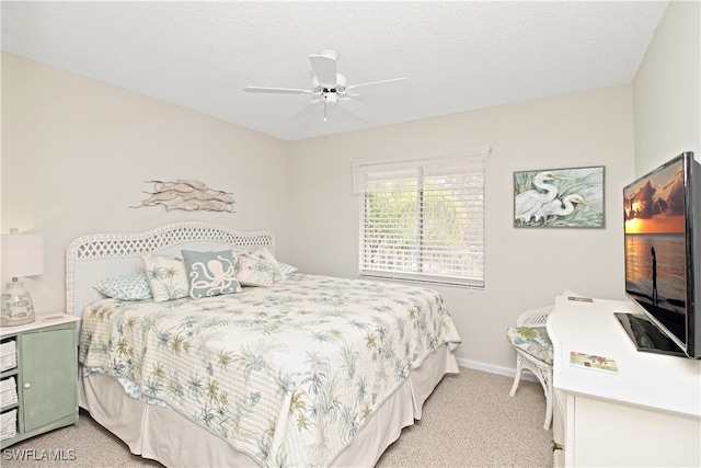 bedroom with ceiling fan, light colored carpet, and a textured ceiling