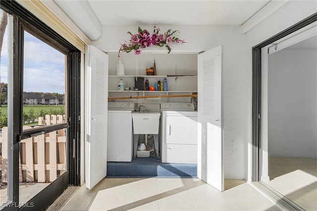 interior space with sink, light tile patterned floors, and washing machine and dryer